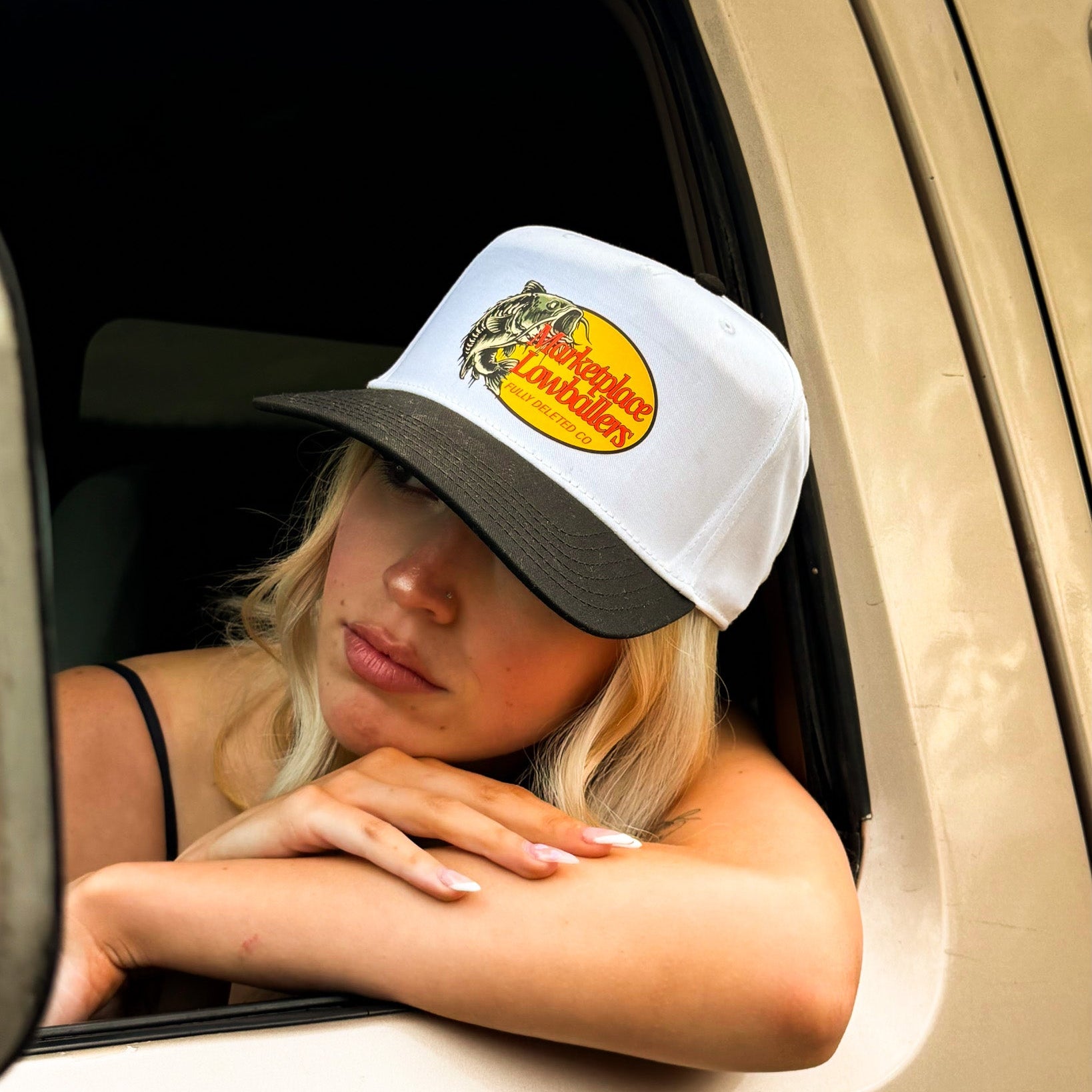 Person wearing a cap with a logo, sitting inside a vehicle.