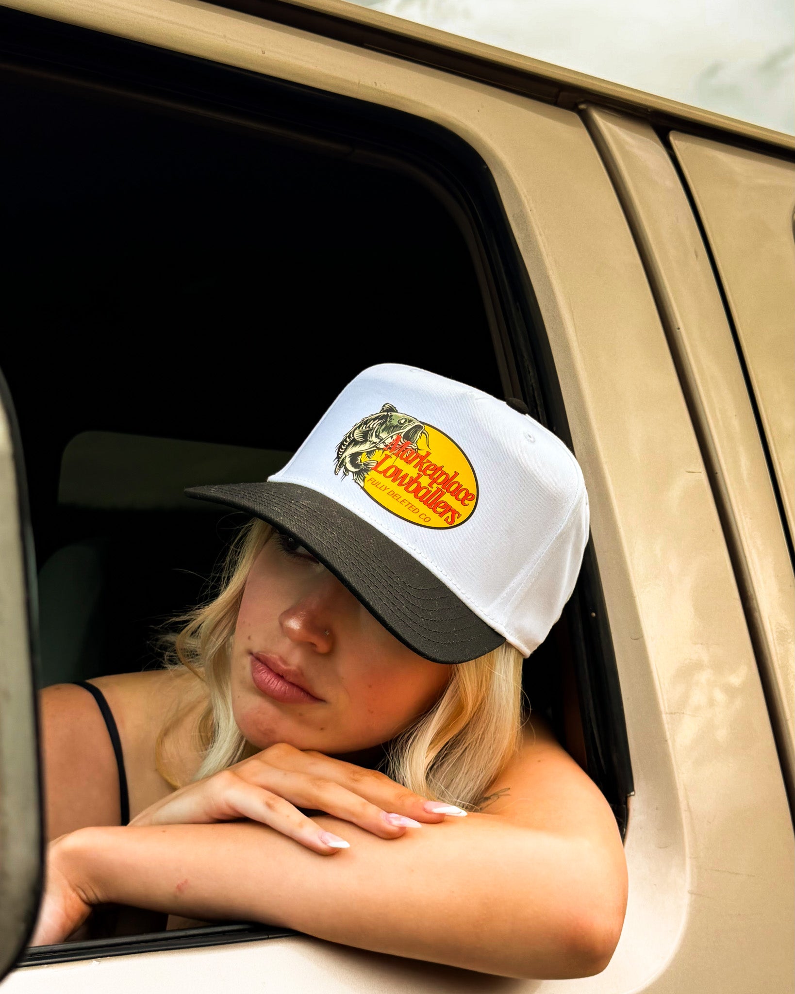 Person wearing a cap with a logo, sitting inside a vehicle.