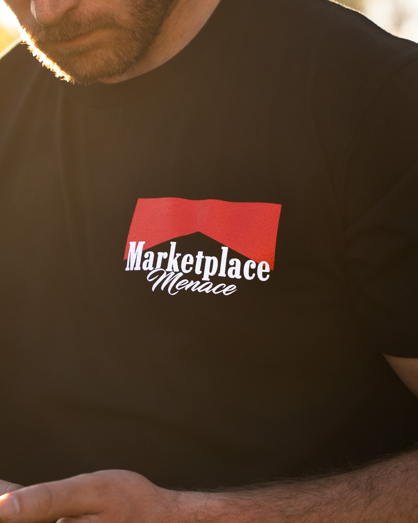 Person wearing a black t-shirt with 'Marketplace Menace' logo