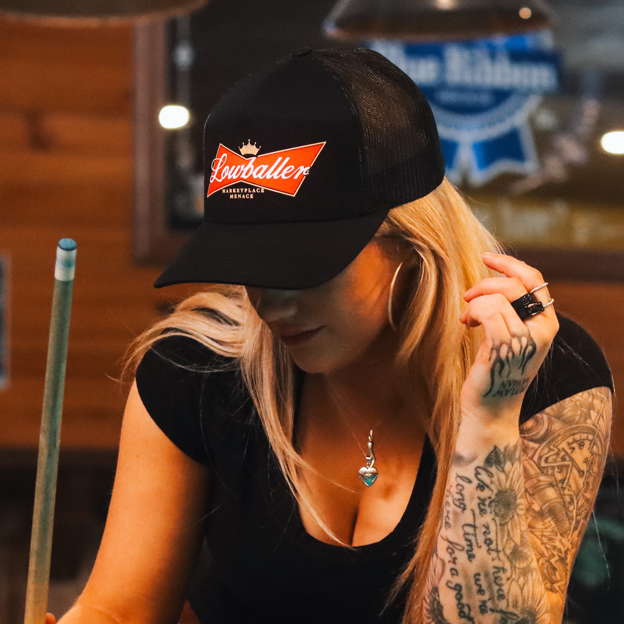 girl indoors wearing black hat with logo