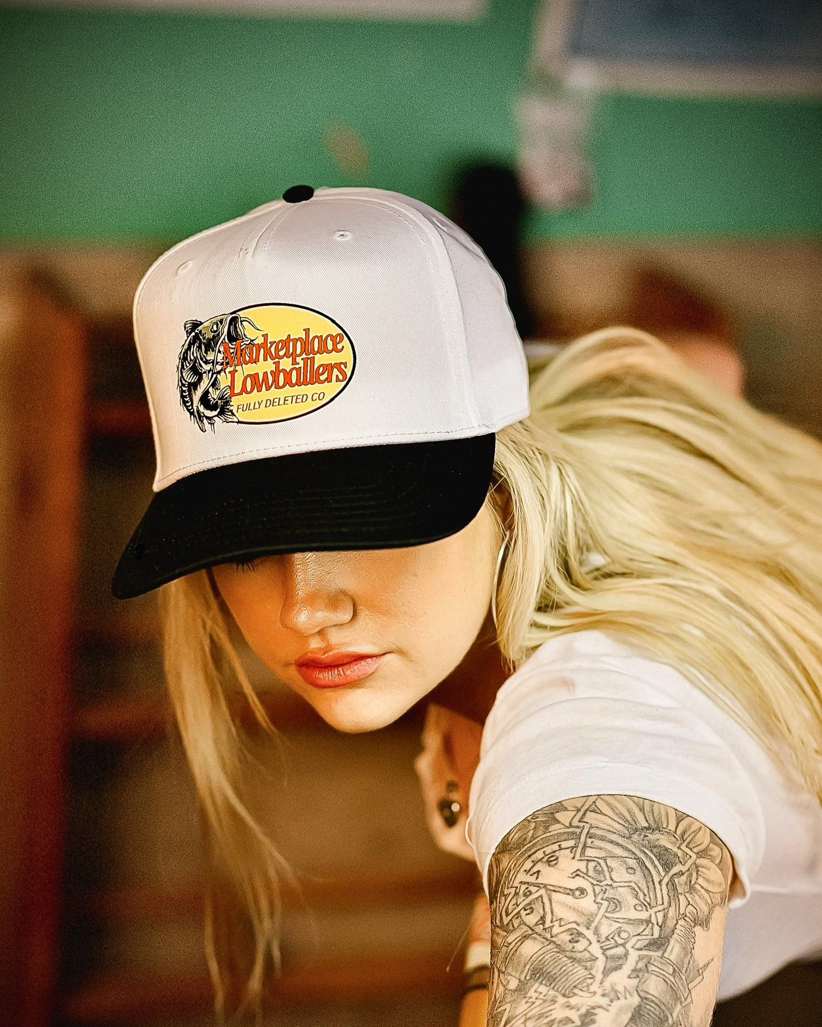 Person wearing a white and black cap with a logo, indoors.