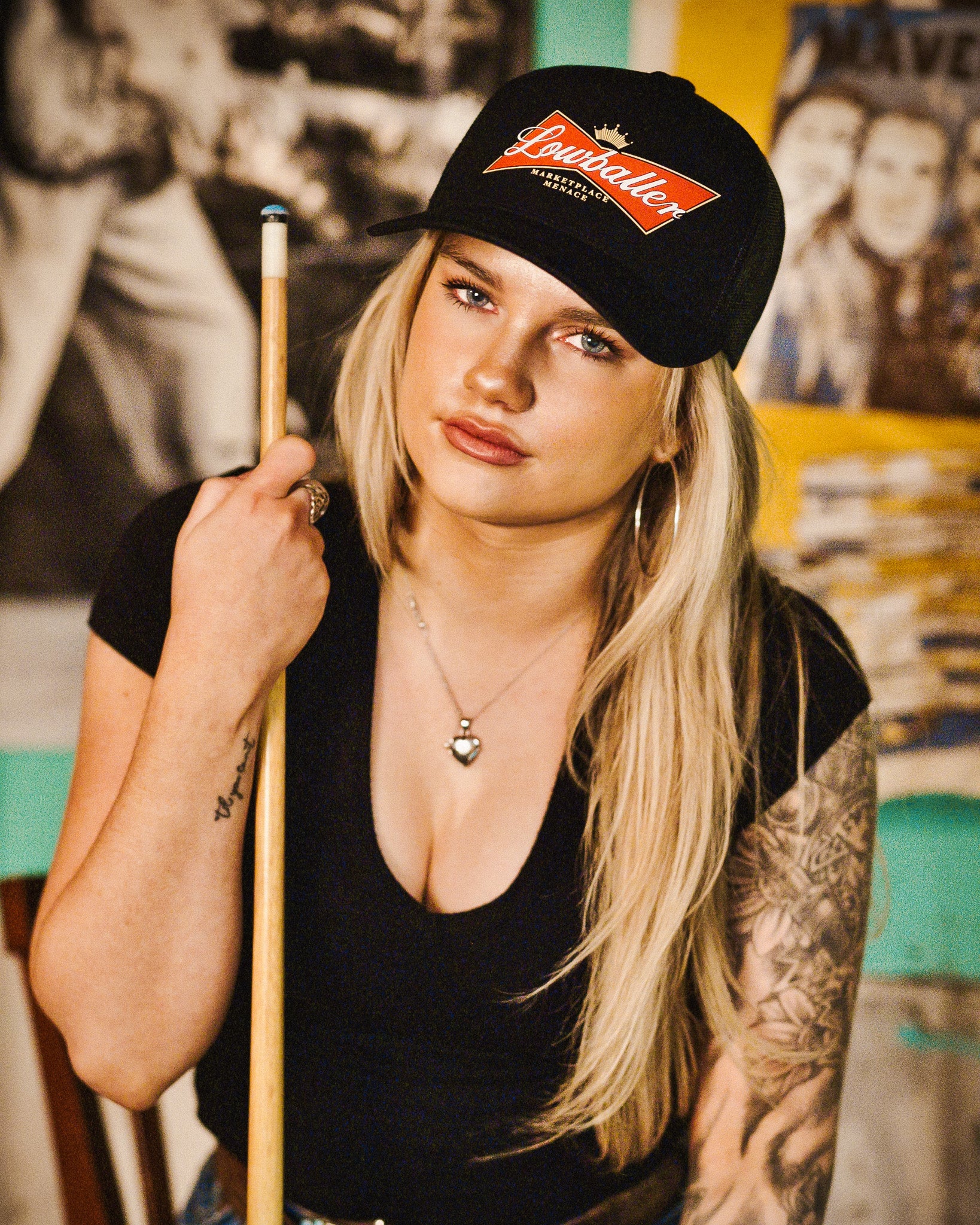 girl with pool que and black hat looking at camera