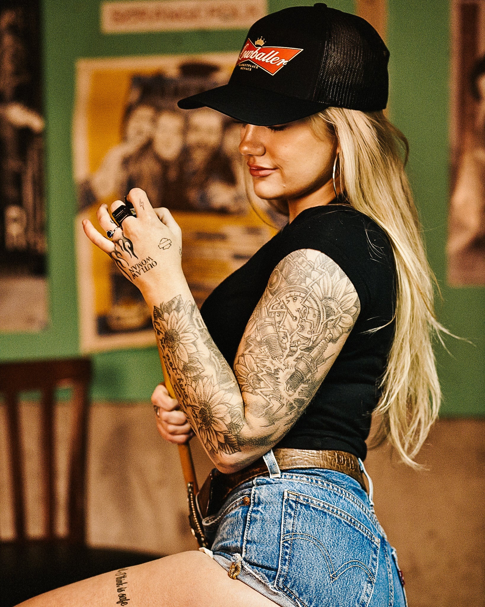 girl indoors, playing pool, wearing black shirt and black hat with logo