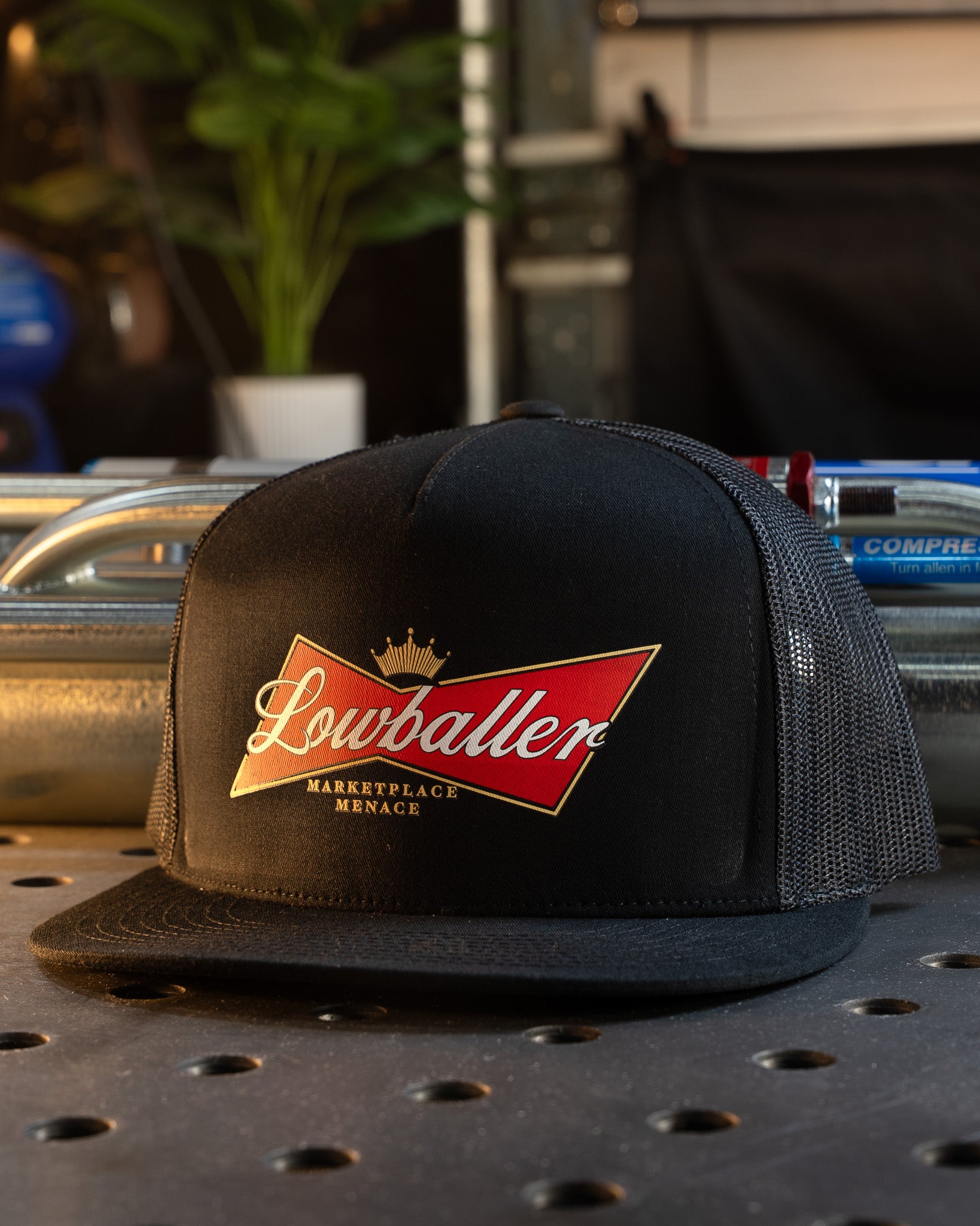 Black cap with a red and gold logo on a metal surface