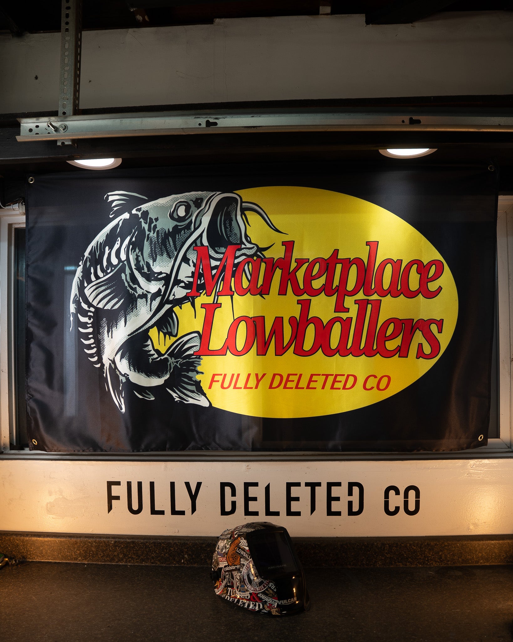 Sign with fish illustration and text 'Marketplace Lowballers Fully Deleted Co' on a vehicle window.